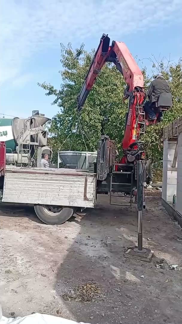A crane truck delivers building materials to the shelter site