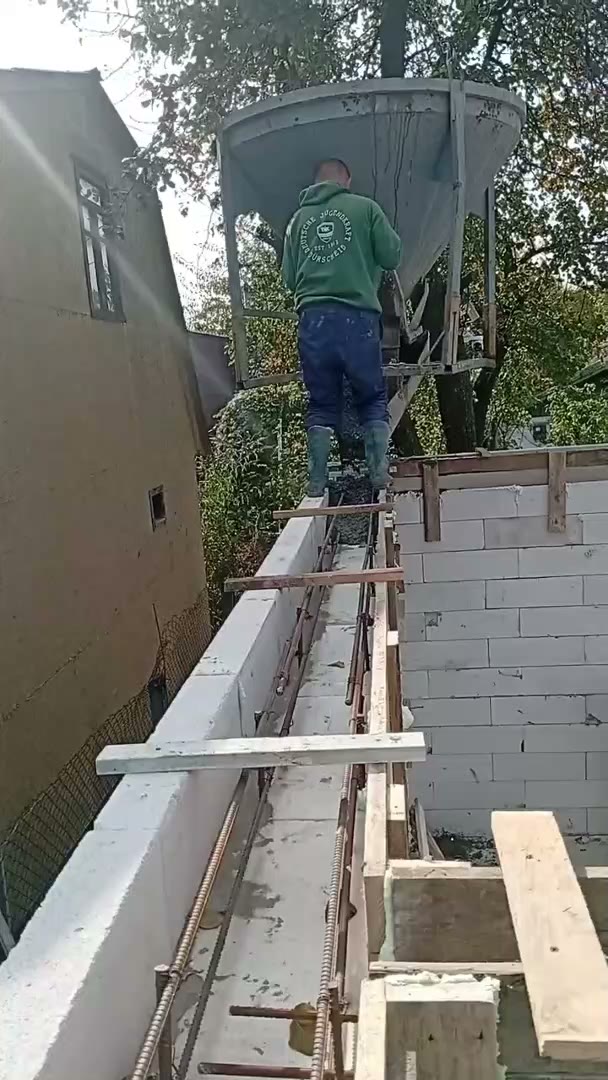 A worker pours concrete into the formwork on top of the shelter walls